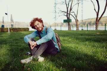 Fototapeta premium Portrait of a young happy ginger man relaxing on the grass