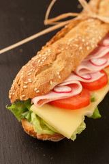 sandwich French baguette, cheese, ham, tomato, radish, lettuce closeup. homemade food. crisp bread