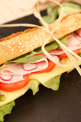 sandwich French baguette, cheese, ham, tomato, radish, lettuce closeup. homemade food. crisp bread