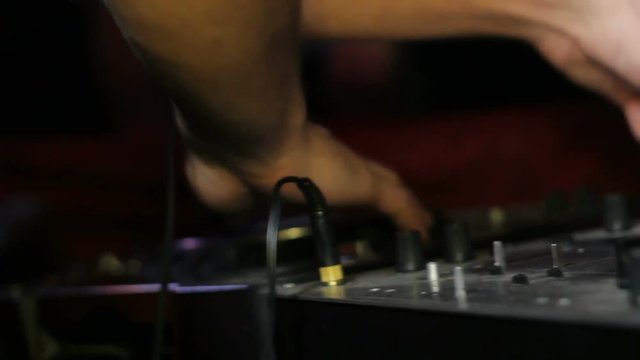 Male DJ Controls sound remote in night club