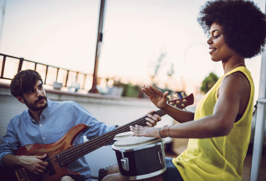 Multirracial young couple playing drums and a guitar