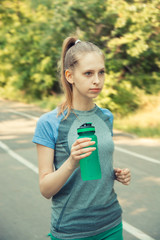 Thirsty fitness girl holding bottle of water