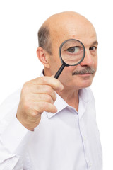 Fototapeta na wymiar elderly man looks at something through a magnifying glass.