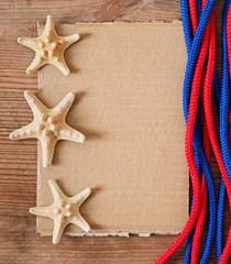 Paper, starfish and rope on the old wooden background.