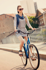 Beautiful woman cycling in the city and wearing sunglasses