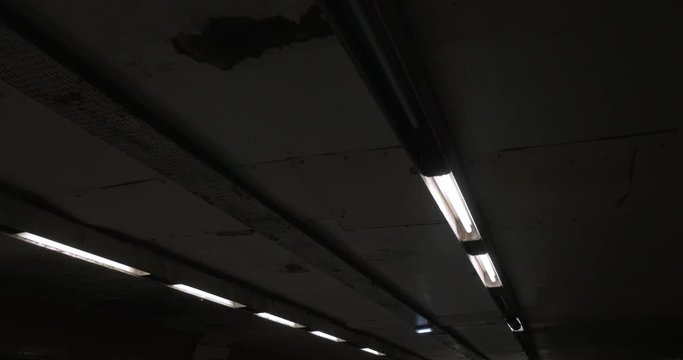 View to the worn grungy ceiling in poor lighted rooms. Shot from moving flat escalator