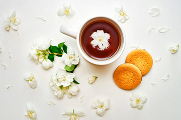 Tea cup with fragrant Jasmine flowers and biscuits in background