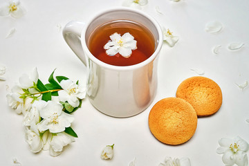 Tea cup with fragrant Jasmine flowers and cookies in background