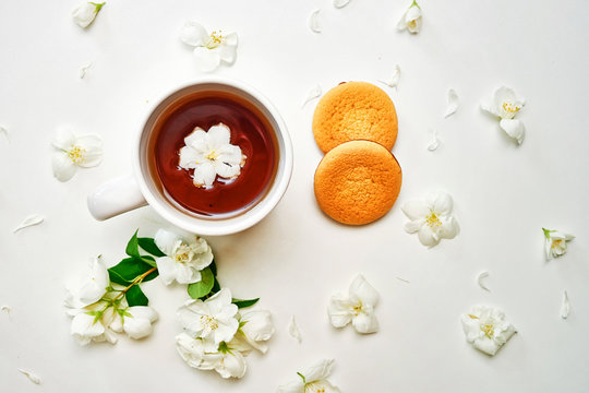 Tea cup with Jasmine flowers and biscuits on white background