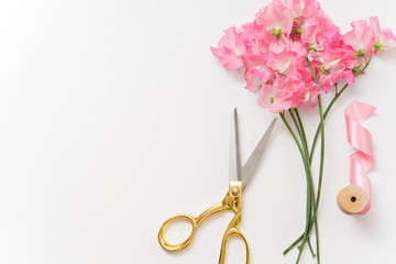 scissors, flowers and ribbon on white table