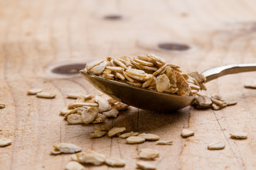 oat flakes on wooden table with steel spoon