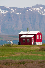 Fototapeta na wymiar Islanda: una casa rossa di legno nella campagna islandese il 20 agosto 2012. Il paesaggio islandese è considerato in tutto il mondo unico e diverso da qualsiasi altro sul pianeta