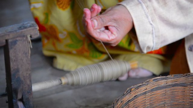 Elderly ,Burmese woman winding thread onto a quickly spinning spool as part of a manufacturing process for the production of yarn at a village in Myanmar. Video 1920x1080