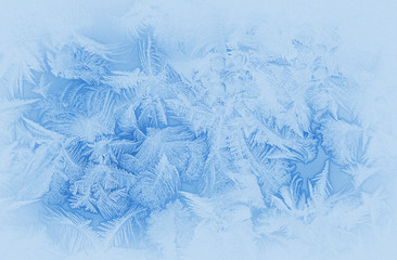 Bright blue frost pattern on a window glass in the winter (as an abstract winter background), retro...