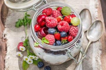 Berry fruits and yogurt with granola in sunny day