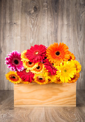 Box of mixed flowers on wooden background