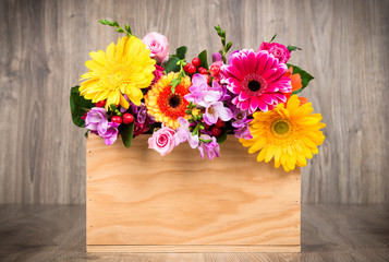 Box of mixed flowers on wooden background