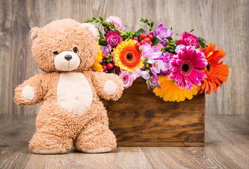 Obraz premium Beautiful flowers and a teddy bear on wooden background