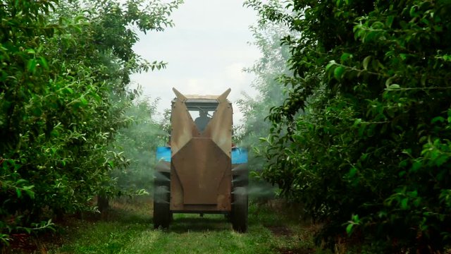 A Rear view of the Fan Sprayer applying Chemicals in an Apple orchard