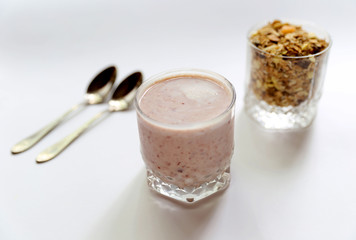 Granolai is for the breakfast in the transparent glass with yogurt, napkins and spoons on white background