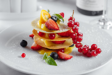 red currants and olives with slices of strawberry and lemon on a white plate