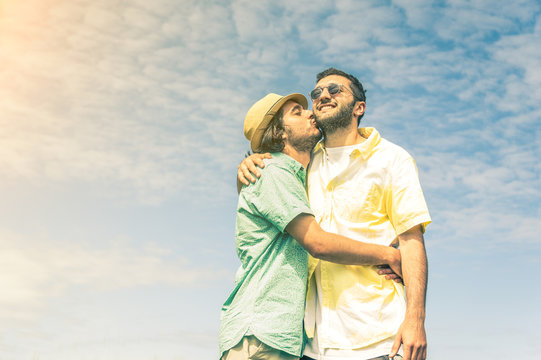 Gay couple in love kissing on a sky background.