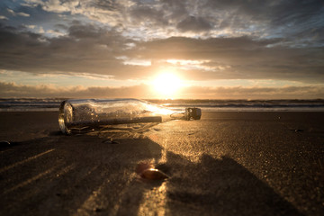Flaschenpost am Strand bei Sonnenuntergang