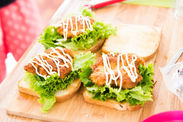 putting sauce on chicken cutlet sandwitch