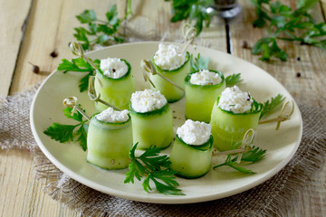Cucumber rolls stuffed with feta cheese, dill and olives on a wo