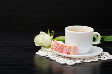 Coffee with milk, Turkish delight, white rose on a black table