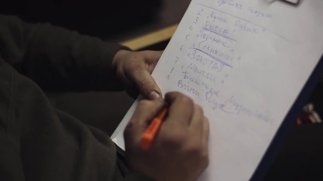 Man sitting on chair and underline words in list on sheet of paper in folder by blue pen