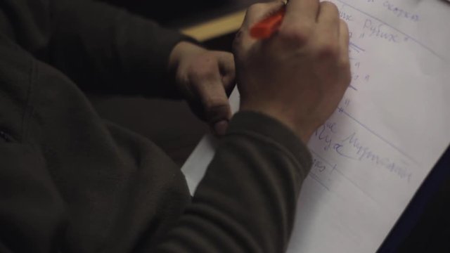 Man sit on chair underline words in list on sheet of paper in folder by pen. Write ticks