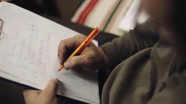 Man sit on chair underline words in list on sheet of paper in folder by blue pen. Writing.