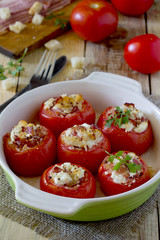 Baked stuffed tomatoes with bacon and feta cheese on rustic tabl