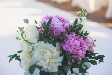 Beautiful wedding interior and table decor, flower decoration with flowers bouquet, with roses, tulips, peonies for outdoor wedding ceremony	