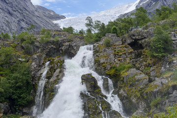 Naklejka na ściany i meble Briksdalsbreen glacier at summer with waterfall from melted ice on foreground. Jostedalsbreen National Park in Norway.