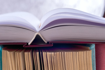 Open book, stack of colorful hardback books on light table. Back to school. Copy space for text