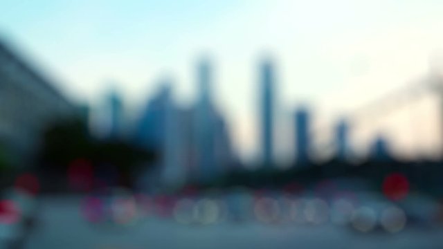 Blurry abstract with fuzzy outlines of urban highrise architecture, standing against an early morning sky, with bokeh effect from cars and traffic in the foreground.