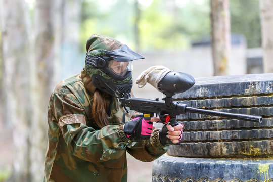 Cool girl with paint gun playing paintball game