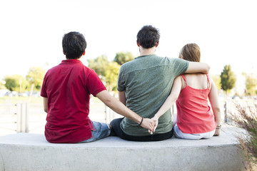 Love triangle, a girl is hugging a guy and he is holding hands with another girl, they are sitting...