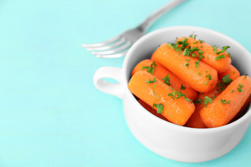 Small baby carrots in soup plate on light blue background