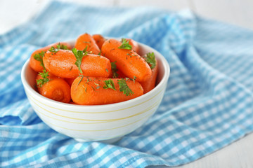Small baby carrots in soup plate on blue napkin