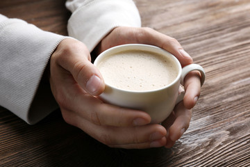 Man holding in hands cup of coffee on wooden background