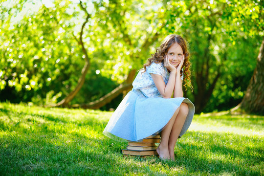 Little girl sitting on stack of books 