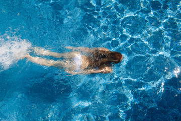 girl in a white bathing suit under the water in the pool