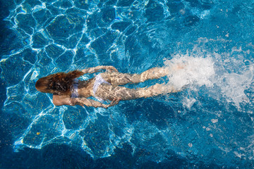 girl in a white bathing suit under the water in the pool