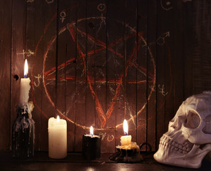 Evil candles against wooden background with pentagram