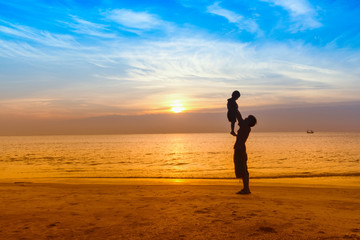 Father and son play on the Beach in sunrise silhouette shot