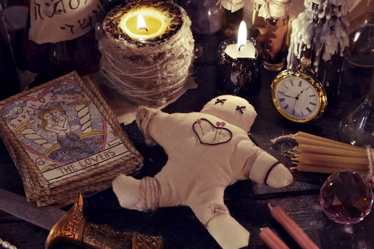Close up of woodoo doll, knife, burning candles and magic objects