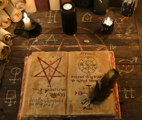 Black candles and open magic book with pentagram
